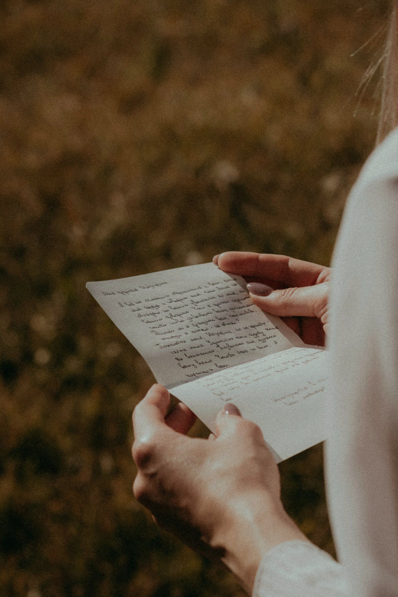 Hands holding a handwritten welcome letter in a golden field