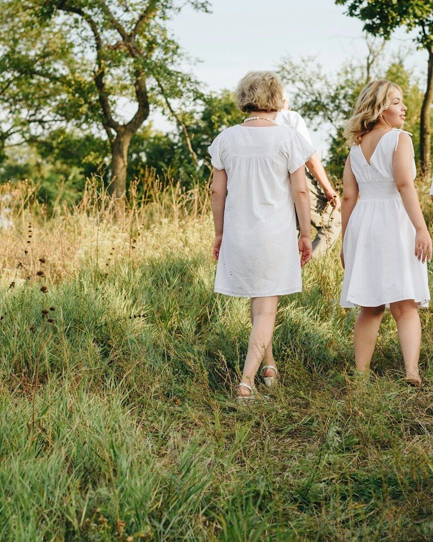 Women in white dresses walking together into a summer meadow